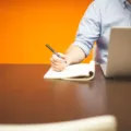Seseorang sedang menggunakan laptop kerja modern di atas meja kantor untuk menyelesaikan pekerjaan