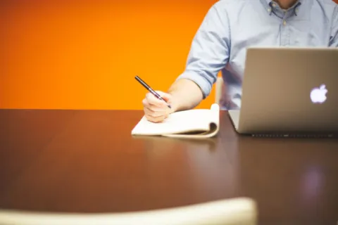 Seseorang sedang menggunakan laptop kerja modern di atas meja kantor untuk menyelesaikan pekerjaan