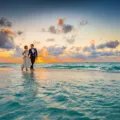 Pasangan menikmati pemandangan matahari terbenam di pantai untuk wisata pasangan romantis