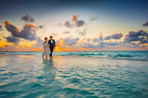 Pasangan menikmati pemandangan matahari terbenam di pantai untuk wisata pasangan romantis