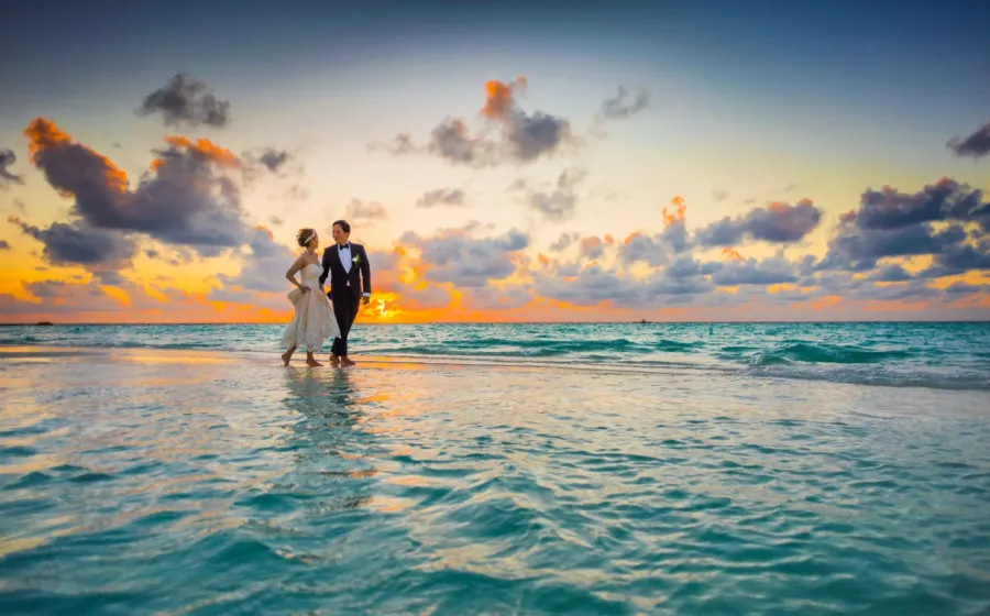Pasangan menikmati pemandangan matahari terbenam di pantai untuk wisata pasangan romantis